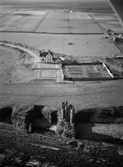 Oblique aerial view centred on the remains of Old Keiss Castle with Keiss Castle and walled garden adjacent, looking to the NW.