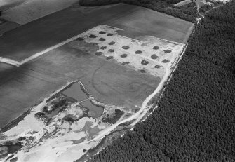 Oblique aerial view centred on the cropmarks of an enclosure, linear features and pits at Dalladies, with the sand and gravel quarry adjacent, looking to the N.