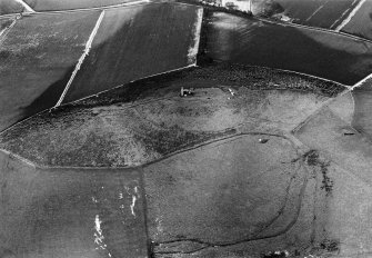 Oblique aerial view centred on the remains of the tower house and fort at Dunideer, looking to the NE.