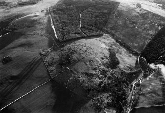 Oblique aerial view centred on the remains of a hut circle, cairns and cultivation remains at Bar Hill, looking to the SSW.