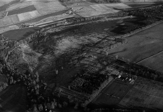 Oblique aerial view centred on the cropmarks of the field boundaries and rig at Dunnecht House with the kennels adjacent,  looking to the NE.