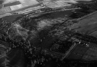 Oblique aerial view centred on the cropmarks of the field boundaries and rig at Dunnecht House with the kennels adjacent,  looking to the NE.