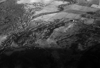 Oblique aerial view centred on the remains of hut circles, clearance cairns, buildings and enclosures at Wester Clune, looking to the NE.