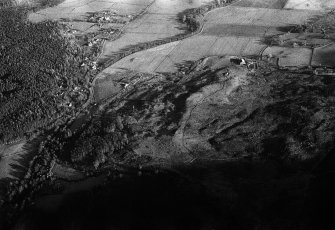 Oblique aerial view centred on the remains of hut circles, clearance cairns, buildings and enclosures at Wester Clune, looking to the NE.