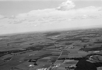 General oblique aerial view centred on the village of Drumoak, the A93 and the surrounding plantations, looking to the NE.