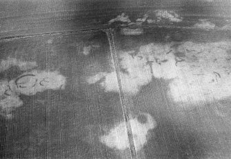 Oblique aerial view centred on the cropmarks of the unenclosed settlement, ring ditch, souterrains and pits at Burnhead of Monboddo, looking to the NNW.
