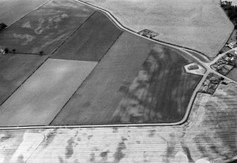 Oblique aerial view centred on the cropmarks of the pit defined cursus, pits and rig at Inchbare and Stracathro, looking to the SW.