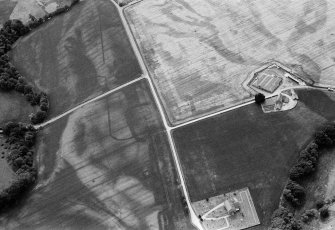Oblique aerial view centred on the cropmarks of the Roman Temporary Camp and Fort with the churchyard adjacent at Stracathro, looking to the SW.
