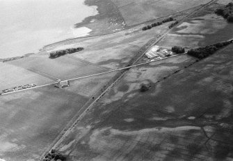 Oblique aerial view centred on the cropmarks of the Roman Temporary Camp, unenclosed settlement, linear features, pits and rig at Gilrivie, looking to the SW.