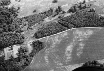 Oblique aerial view centred on the cropmarks of the unenclosed settlement, roundhouses, souterrains, pits and rig at Kinnaird Castle, looking to the SE.