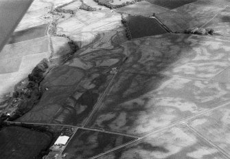 Oblique aerial view centred on the cropmarks of the unenclosed settlement, souterrain, rectinlienar enclosure, rig and pits at Chapelton and Boysack, looking to the SE.