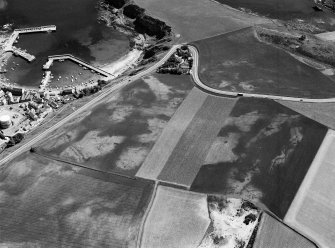 Oblique aerial view centred on the cropmarks of the unenclosed settlement and field system at Braehead with Stonehaven adjacent, looking to the ESE.