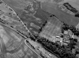 Oblique aerial view centred on the cropmarks of the unenclosed settlement, ring ditches, souterrain, pits and rig at Pitmuies, looking to the SE.