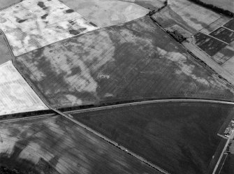 Oblique aerial view centred on the cropmarks of the unenclosed settlement, ring ditches, enclosures, rig and pits at Inverkeilor and Ironshill, looking to the E.