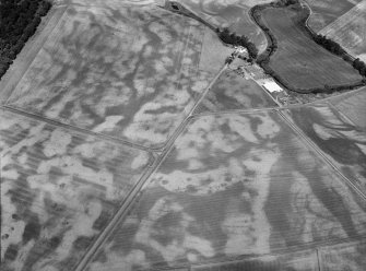 Oblique aerial view centred on the cropmarks of the unenclosed settlement, roundhouses, rig and pits at Chapelton and Boysack, looking to the NNW.