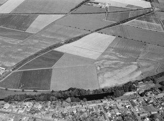 Oblique aerial view centred on the cropmarks of the pit defined cursus, unenclosed settlement and rig with Friockheim adjacent, looking to the NW.