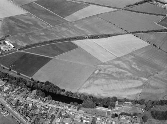 Oblique aerial view centred on the cropmarks of the pit defined cursus, unenclosed settlement and rig with Friockheim adjacent, looking to the NW.