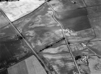 Oblique aerial view centred on the cropmarks of the unenclosed settlement, ring ditches and rig at West Mains of Hedderwick, looking to the SW.
