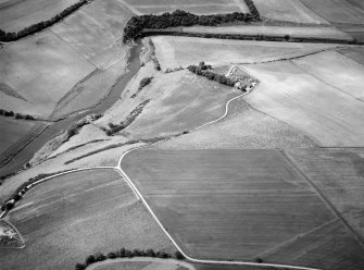 Oblique aerial view centred on the cropmarks of the enclosures and field system with the farmhouse and chapel adjacent at Chapeltown, looking to the NW.