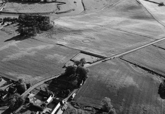Oblique aerial view centred on the cropmarks of the barrow at Boat of Hatton with the pit defined cursus adjacent, looking to the SW.