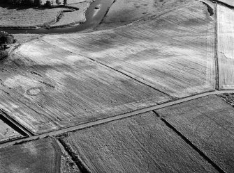 Oblique aerial view centred on the cropmarks of the pit defined cursus and pits at Mill of Fintray with the barrow adjacent, looking to the SW.