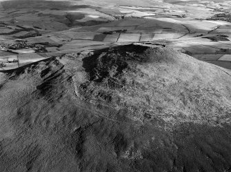 Oblique aerial view centred on the remains of the vitrified fort at Tap O' Noth, looking to the SE.