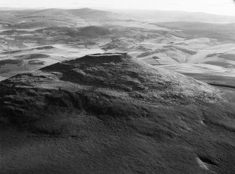 Oblique aerial view centred on the remains of the vitrified fort at Tap O' Noth, looking to the SW.