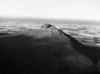 Oblique aerial view centred on the remains of the fort at Mither Tap of Bennachie, looking to the NE.