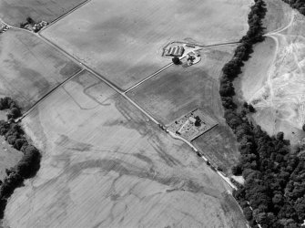 Oblique aerial view centred on the cropmarks of the Roman Temporary Camp, ring ditch and pits with Strathcathro Parish Church adjacent, looking to the W.