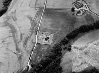 Oblique aerial view centred on the cropmarks of the Roman Temporary Camp, ring ditch and pits with Strathcathro Parish Church adjacent, looking to the SW.