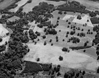 Oblique aerial view centred on the cropmarks of the ring ditches and rig at Kinnaird Park with Kinnaird Castle and Policies adjacent, looking to the SSE.
