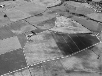 Oblique aerial view centred on the cropmarks of a circular enclosure at Myreside with the farmstead adjacent, looking to the S.