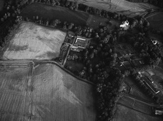 Oblique aerial view centred on the cropmarks of the unenclosed settlement, ring ditches, possible souterrain and pits with Glenbervie House and Policies adjacent at Glenbervie, looking to the SSE.