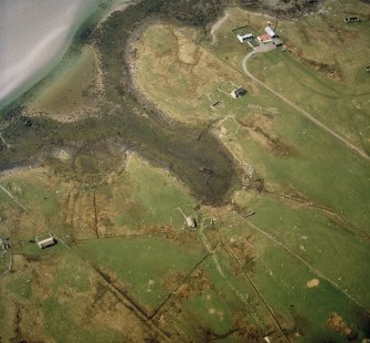 Oblique aerial view centred on the remains of the buildings with the remains of the chambered cairn and standing stone adjacent, taken from the ESE.