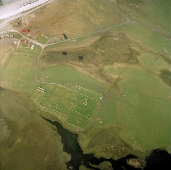 Oblique aerial view centred on the burial-ground and the remains of the church, taken from the SSE.