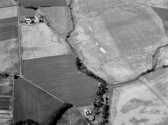 Oblique aerial view of the cropmarks of the enclosure at West Mains of Colliston with the cropmarks at Newton in the foreground, looking to the WSW.