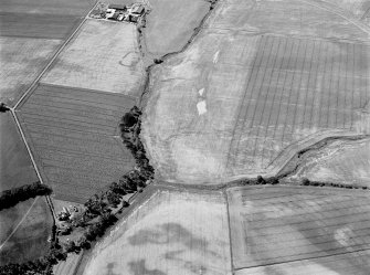 Oblique aerial view of the cropmarks of the enclosure at West Mains of Colliston with the cropmarks at Newton in the foreground, looking to the SSW.