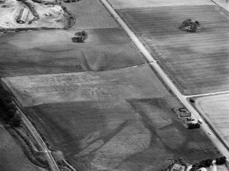 Oblique aerial view centred on the cropmarks of the ring ditches and pit alignment at Fullerton, looking to the SSE.