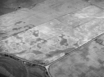 Oblique aerial view centred on the cropmarks of the square barrow, roundhouses, subrectangular buildings, ring ditch and pits at Kinchyle and Little Kildrummie, looking to the W.