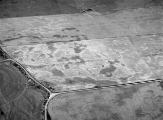 Oblique aerial view centred on the cropmarks of the square barrow, roundhouses, subrectangular buildings, ring ditch and pits at Kinchyle and Little Kildrummie, looking to the SW.