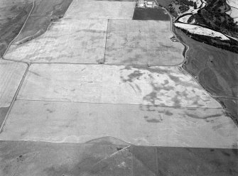 Oblique aerial view centred on the cropmarks of the square barrow, roundhouses, subrectangular buildings, ring ditch and pits at Kinchyle and Little Kildrummie, looking to the NE.