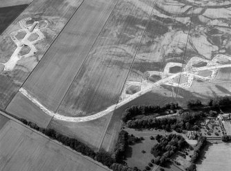 Oblique aerial view centred on the cropmarks of the enclosure and the former airfield at Brackla House, looking to the W.