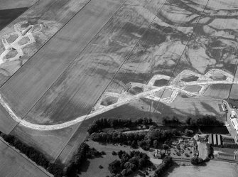 Oblique aerial view centred on the cropmarks of the enclosure and the former airfield at Brackla House, looking to the WNW.