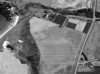 Oblique aerial view centred on the cropmarks of the ring ditches at Sandend, looking to the ENE.