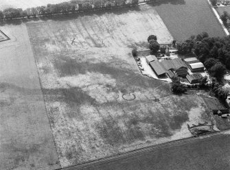 Oblique aerial view centred on the cropmarks of the ring ditches, pits and rig, with the farmstead adjacent at Mains of Balbegno, looking to the S.
