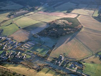 Oblique aerial view centred on the visitor centre, experimental archaeology site and the remains of the enclosure with the village adjacent, taken from the NNW.
