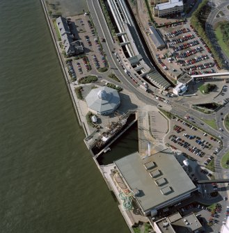 Oblique aerial view centred on the harbour and the Discovery visitor centre, with the leisure centre and railway station adjacent, taken from the ENE.
