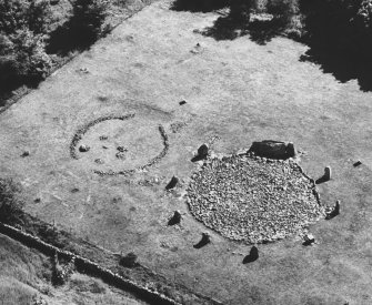 Oblique aerial view centred on the remains of the stone circle and enclosed cremation cemetery at Loanhead of Daviot, looking to the SSE.