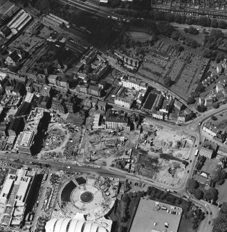 Oblique aerial view centred on the construction site, with exhibition centre and Queensbury House adjacent, taken from the S.