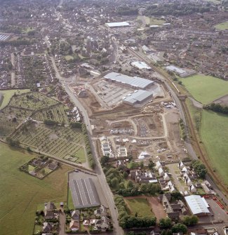 Oblique aerial view centred on the site of the market, the shopping centre and new housing, taken from the SE.